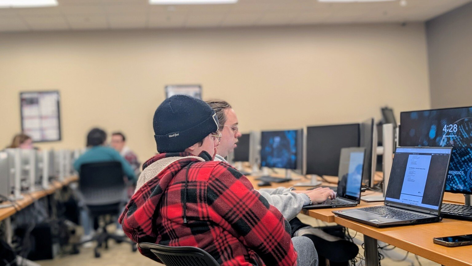 Students working side by side through a cybersecurity incident exercise in a computer lab
